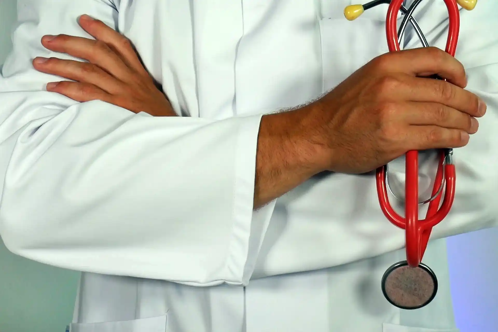 Doctor with crossed arms holding red stethoscope